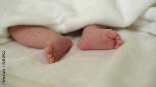 Baby's little legs under white blanket. Newborn - happiness for family. Concept of care for baby. Back view