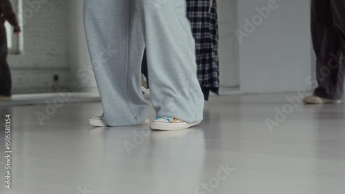 Ground level shot of legs of unrecognizable female dancers in streetwear practicing hip hop moves in studio