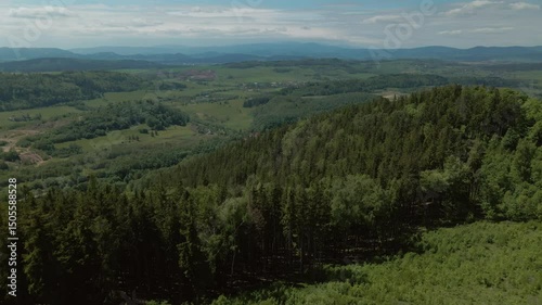 Aerial view of dense green forest and open terrain spreading across hills and valleys around Chełmiec mountain near Boguszów-Gorce in Lower Silesia