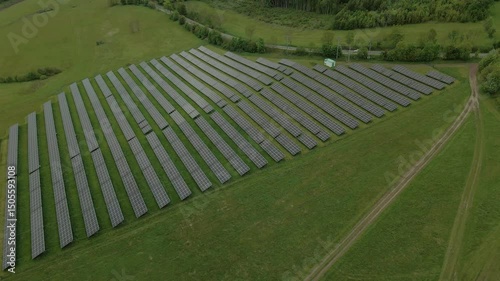 Aerial view of a large field filled with solar panels in the countryside near Boguszów-Gorce, Poland surrounded by green hills and farmland
