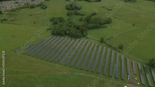 Large field of solar panels positioned beside forest and green meadows near Boguszów-Gorce and Chełmiec Mountain, viewed from above