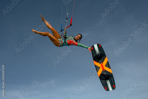young brunette woman in sports swimsuit extreme kite riding in the sea on the waves