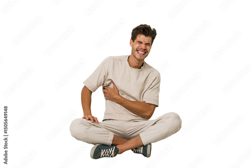 Young caucasian man sitting on the floor isolated on white background having a liver pain, stomach ache. Young caucasian man sitting on the floor isolated on white background having a liver pain, stomach ache.