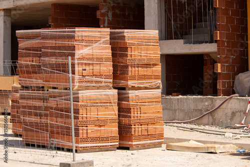 A tall stack of bricks packed on a pallet at a construction site. High strength building materials
