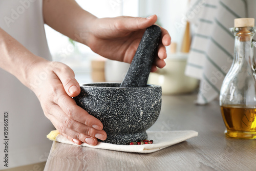 Schilderij op canvas Woman with mortar and pestle at wooden table in kitchen, closeup