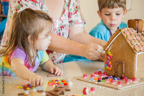 Kids decorating gingerbread house with lollies for christmas photo