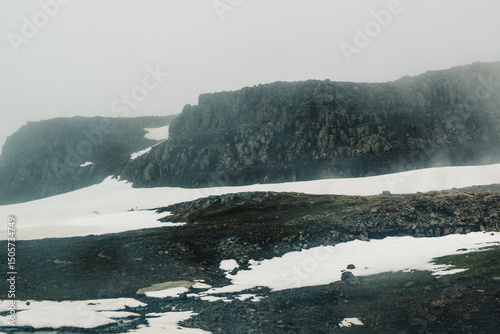 Snow-covered rocky slopes in Seydisfjordur shrouded in mist, East Iceland...