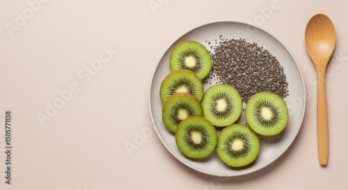 Top view of fresh kiwi slices and chia seeds on ceramic plate with wooden spoon on pastel background