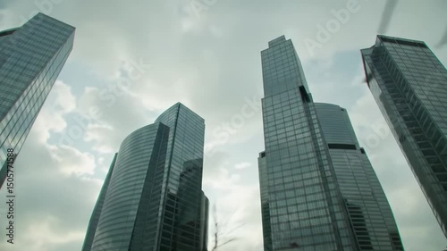 Wallpaper Mural Tall glass skyscrapers dominate the skyline as clouds swirl above. The setting captures the vibrant energy of a city, showcasing architectural brilliance during daylight hours. Torontodigital.ca