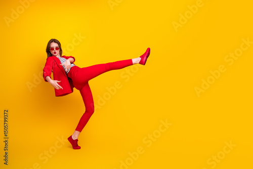 Adorable stylish woman in a vibrant red outfit posing against a vivid yellow background, emphasizing energy and modern fashion
