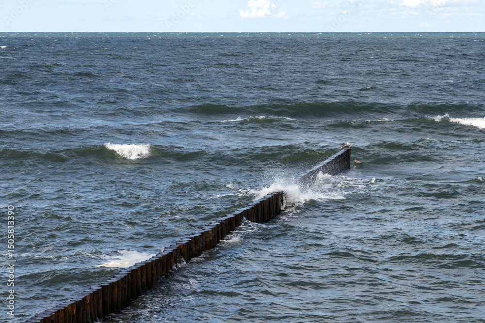 Fototapeta premium Dynamic image showcasing ocean waves striking a wooden breakwater