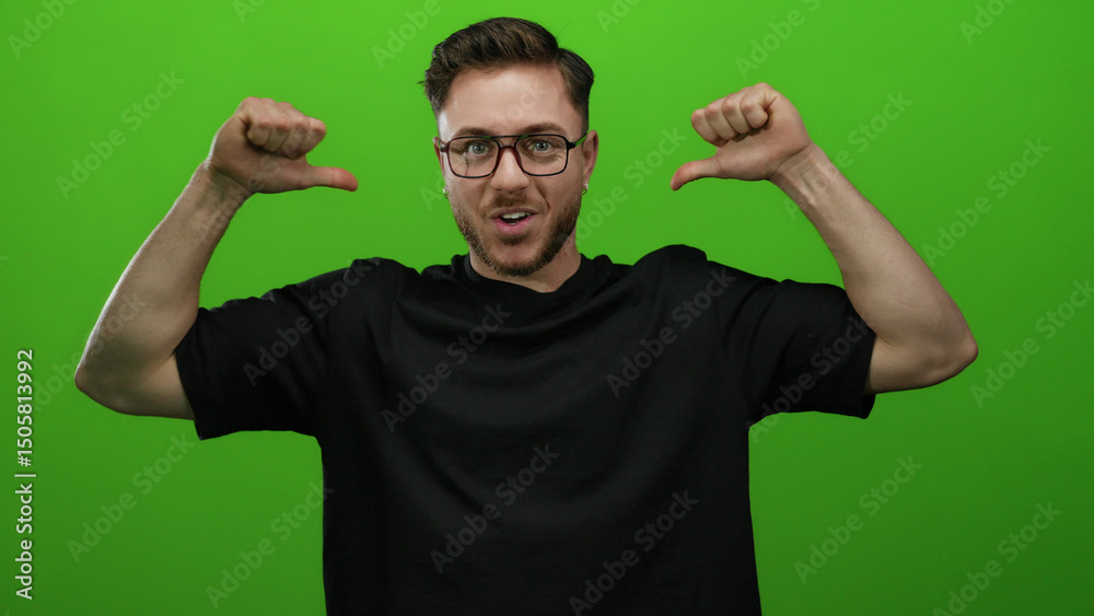 Fototapeta premium Caucasian man with glasses and beard pointing at himself against a bright green wall background wearing a black shirt and smiling confidently.