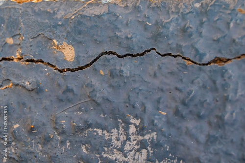 peeling blue colored wall with a crack and cobwebs inside