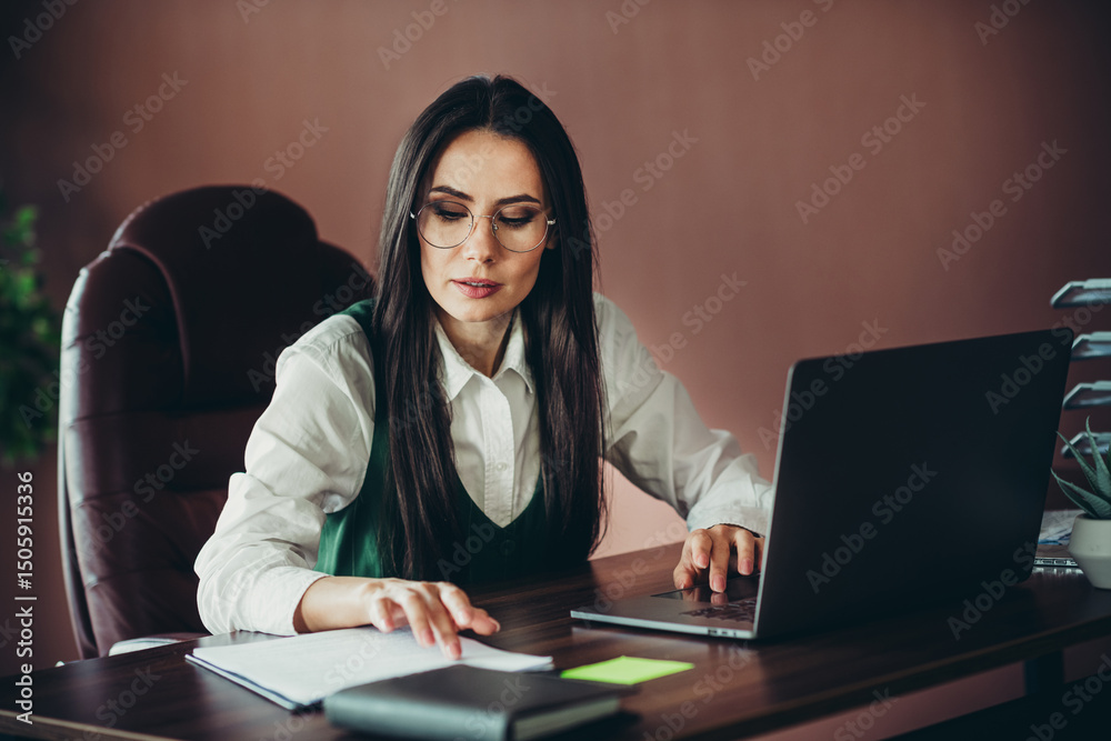 Confident professional businesswoman working in an office environment, showcasing elegance and professionalism during a focused task Confident professional businesswoman working in an office environment, showcasing elegance and professionalism during a focused task