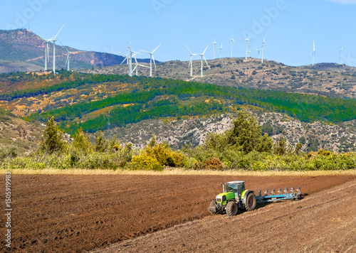 Wallpaper Mural Plowing field at windpower mountains. Tractor Plough Plowed. Ploughing, Soil Tillage. Agricultural Tractor on Cultivation Field, Sowing Seeds. Tractor on Field Cultivating. Wind farm Wind turbines. Torontodigital.ca