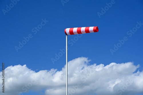 Konstfotografi red and white windsock against blue sky and white cumulus clouds