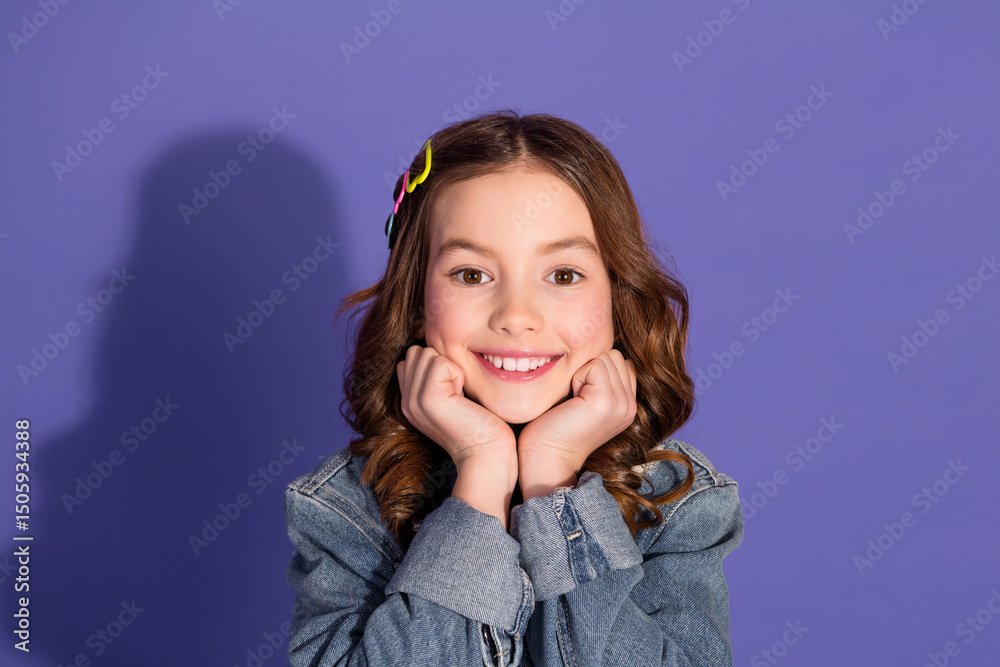 Charming young girl posing on a vibrant purple background wearing a stylish denim jacket and radiant smile. Charming young girl posing on a vibrant purple background wearing a stylish denim jacket and radiant smile.