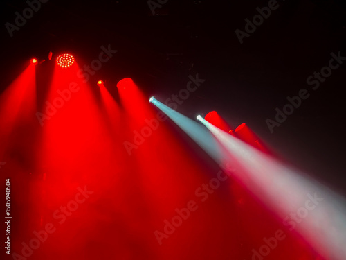 Vibrant dramatic red and white stage light beams cut through hazy darkness creating atmospheric lighting effect for concerts, parties, events, and shows.