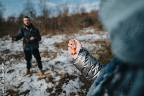 Two hikers enjoy a winter day walk in a snowy landscape, one holding a navigational tool while the other observes.