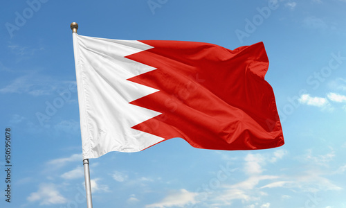 Bahrain national flag with red and white serrated design flying against clear blue sky