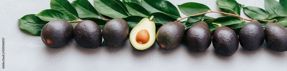 Fototapeta premium A bunch of avocados with one cut open. The avocados are black and the one with the cut open is the only one that is visible