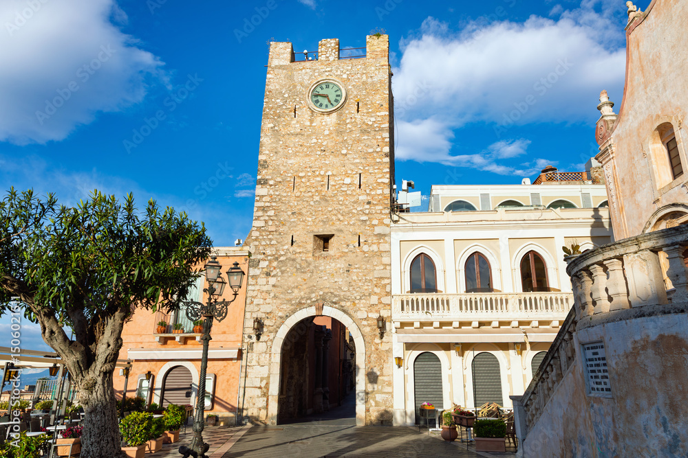 Fototapeta premium Historic stone clock tower located on Piazza IX Aprile in Taormina, Sicily, Italy. Popular tourist attraction in Taormina with scenic views, traditional buildings and Mediterranean architecture.