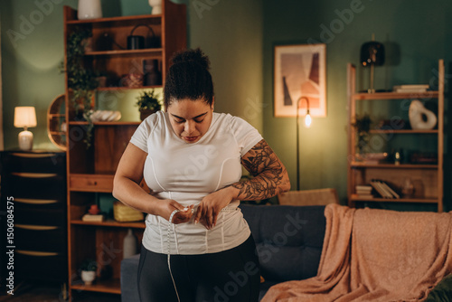 African American woman measures waist line with measuring tape in morning