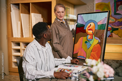 Fotografie Artist discussing contemporary painting with art curator in studio