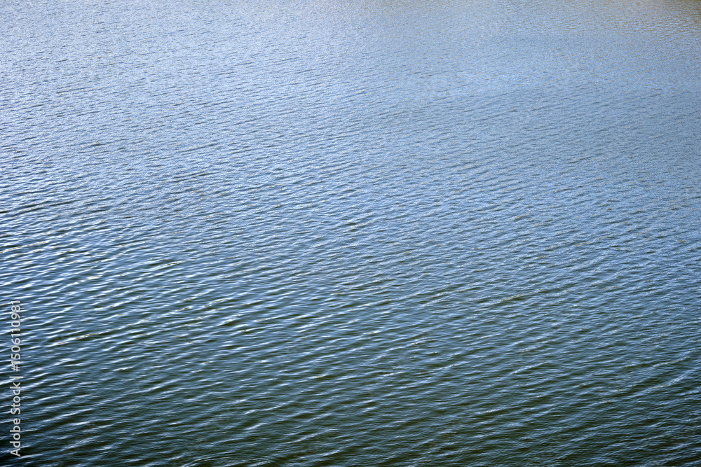 Calm rippling water surface with subtle reflections and gentle waves Calm rippling water surface with subtle reflections and gentle waves