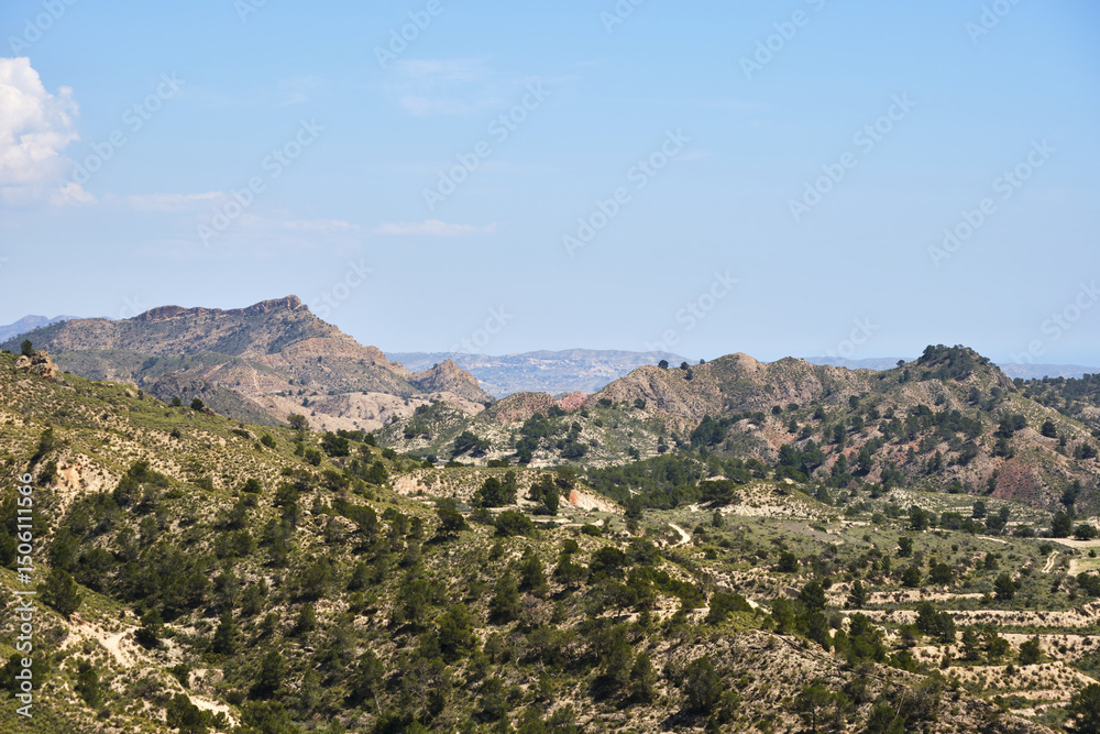 Obraz premium Expansive mountain landscape with rolling hills and greenery under a clear blue sky