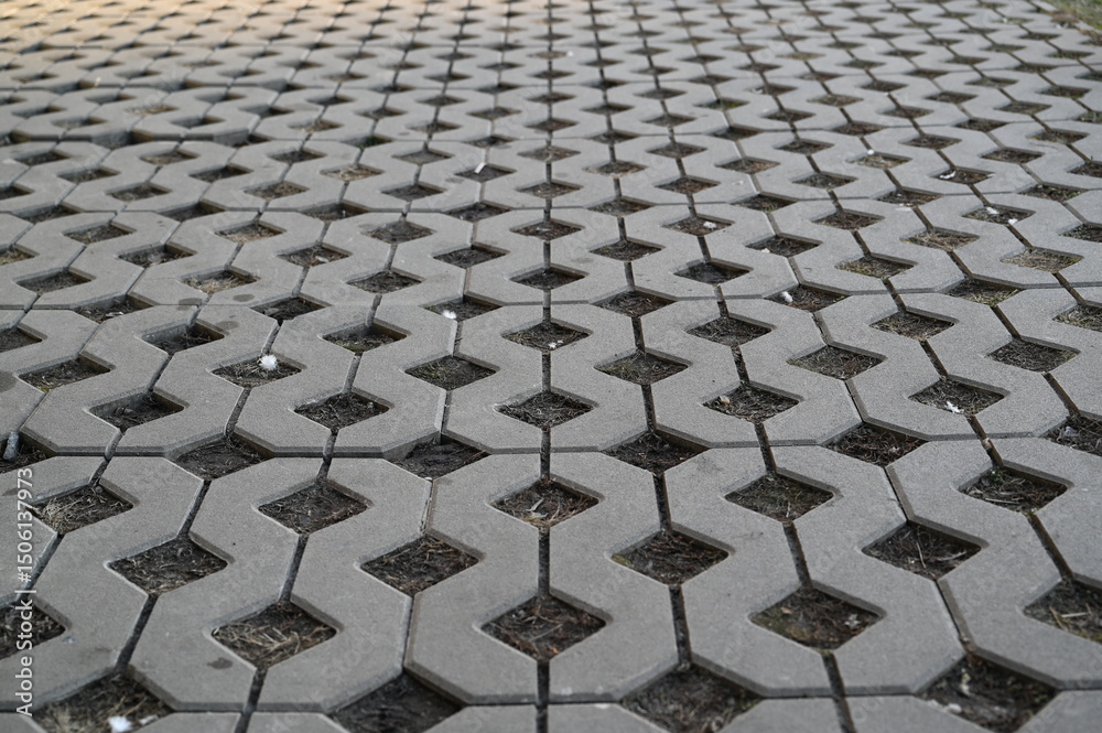 Fototapeta premium Background texture of square tiles made of gray natural stone. Concrete street covering of road, geometric paving pattern, green lawn and eco parking, green parking, sustainable development city 