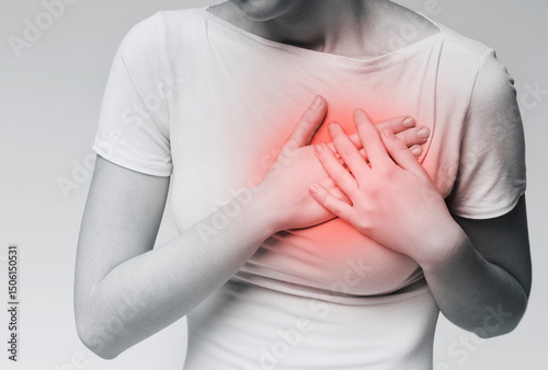 Cropped portrait of young woman with breast pain, touching red sore zone on her chest, black and white photo