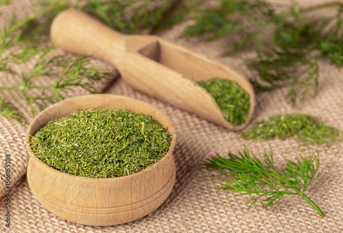 Dried chopped dill in a wooden bowl and sprigs of fresh dill