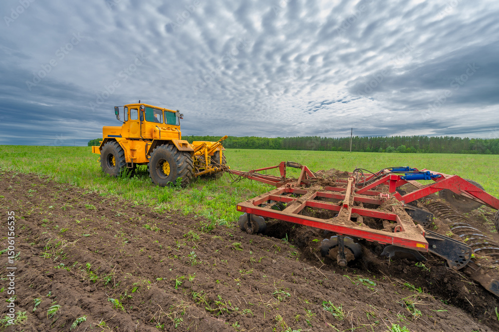 Obraz premium Spring photography, landscape with agricultural machinery, a tractor plows the land, plows a field, birds fly over arable land