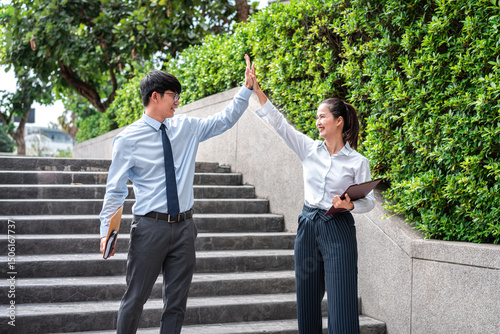 Young business man and businesswoman holding document and giving hand high five after job well done