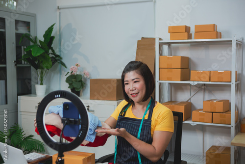 An Asian woman in a yellow t-shirt is live streaming as she sells clothes, engaging warmly with customers, showcasing outfits, answering questions, and promoting items in an energetic