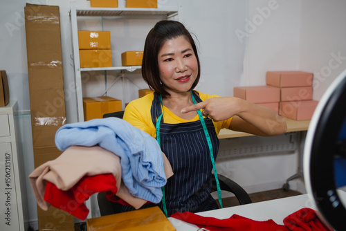 An Asian woman in a yellow t-shirt is live streaming as she sells clothes, engaging warmly with customers, showcasing outfits, answering questions, and promoting items in an energetic