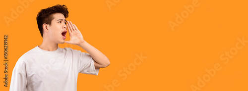 Attention, People. Portrait of asian male model holding hand near mouth, screaming aside at copy space isolated over orange studio background. Guy making offer yelling to free space, banner