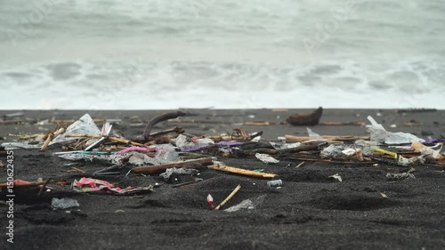Garbage scattered on the beach sand, sea waves in the background