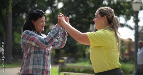 Two happy women hugging greeting each other high five meeting outdoors in the park.