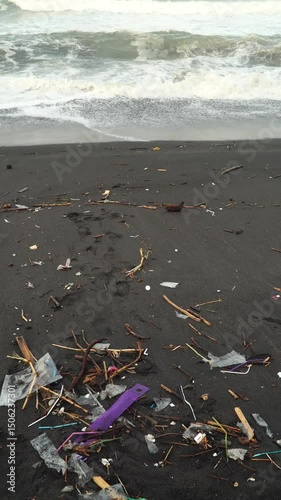 Garbage scattered on the beach sand, sea waves in the background