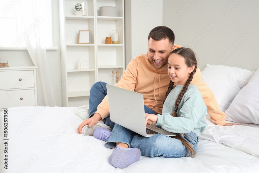 Father and his daughter watching something on laptop together in bedroom Father and his daughter watching something on laptop together in bedroom