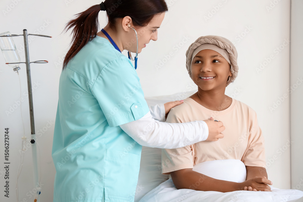 Obraz premium Female doctor with stethoscope listening to African-American girl after chemotherapy in hospital room