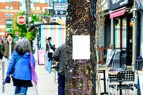 Wooden utility pole with  blank white posted handbill surrounded by thousands of staples from previously posted handbills  out of focus street scene in background  colorful vibrant boho vibe.