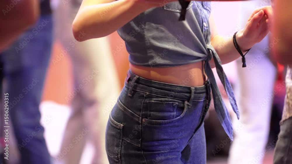 Slow motion salsa dance by a woman wearing knotted shirt and blue jeans