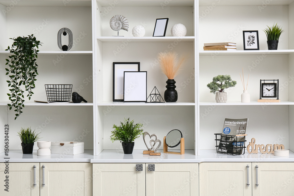 Fototapeta premium Shelf unit with stylish decor, plants and frames in room