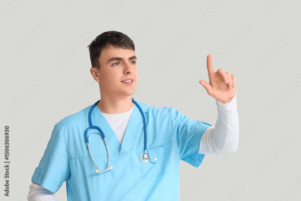 Male doctor pointing at something on light background Male doctor pointing at something on light background