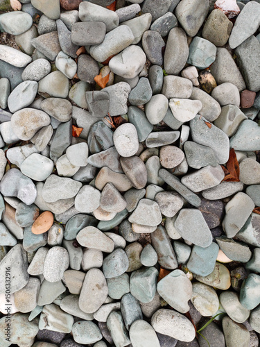 A close-up view of river gravel, showcasing its varied sizes, smooth, rounded textures, and diverse colors ranging from browns and grays to reds and creams. Material used in landscaping, construction