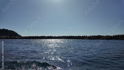 Waves Resting on Sunlight Near Coastal Breakwater