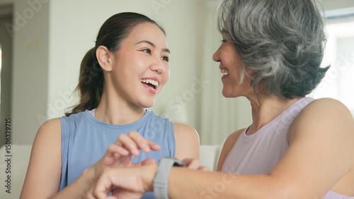 Young adult child give gift AI smart watch IOT app to mature middle age old mum. Love health care older mom asia elder people sit at home sofa happy family wear wrist trace help protect aging life.